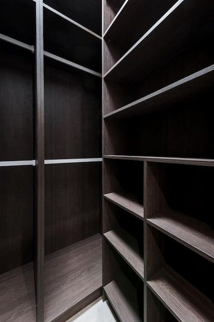 Wide wooden dressing room interior of a modern house Empty brown wooden shelves in the dressing room