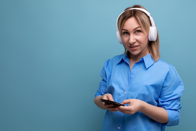 Widescreen photo of a charming european girl in a casual shirt listening to music in big white