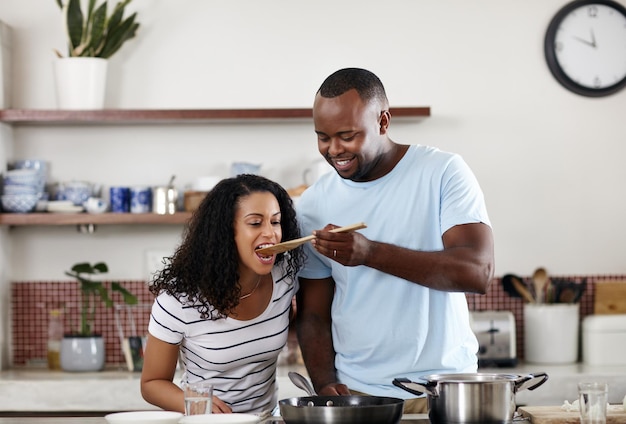 Wie is de betere kok Bijgesneden opname van een jong getrouwd stel dat thuis samen in de keuken kookt