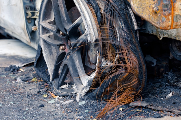 Wiel van verbrande auto verbrande lekke band op de auto is op de grijze asfaltweg om te illustreren