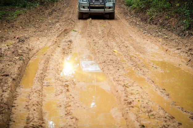 Wielvrachtwagenclose-up in plattelandslandschap met modderige weg