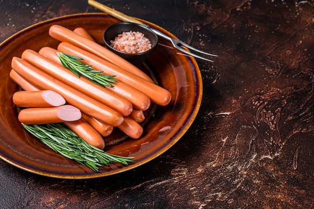 Wiener raw sausages in a rustic plate with herbs