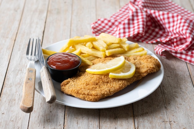 Wiener schnitzel met gebakken aardappelen op houten tafel