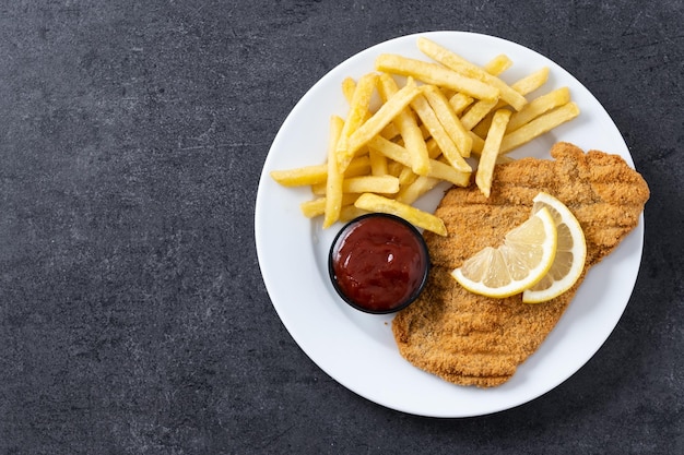 Wiener schnitzel met gebakken aardappelen op zwart leisteen