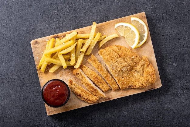 Wiener schnitzel met gebakken aardappelen op zwarte achtergrond