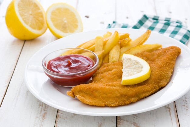 Wiener schnitzel with fried potatoes on white wooden