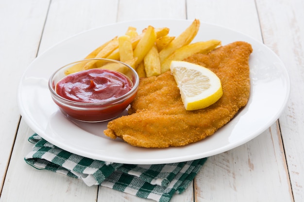 Wiener schnitzel with fried potatoes on white wooden