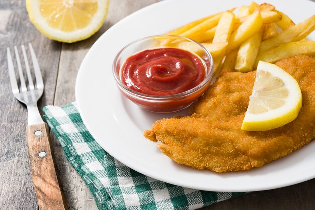 Wiener schnitzel with fried potatoes on wood