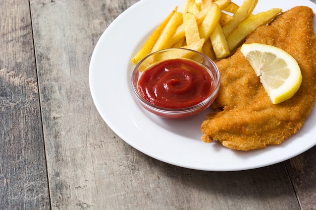 Wiener schnitzel with fried potatoes on wooden