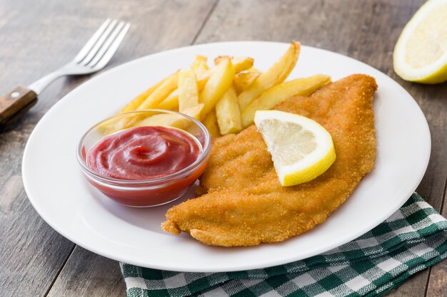 Wiener schnitzel with fried potatoes on wooden