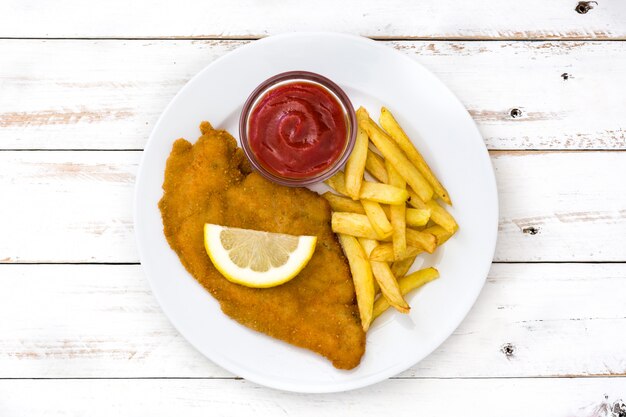 Cotoletta alla milanese con patate fritte su legno