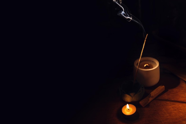 Wierook geurstokjes smeulend op tafel lotushouder en kaars in duisternis zen meditatie mentaal