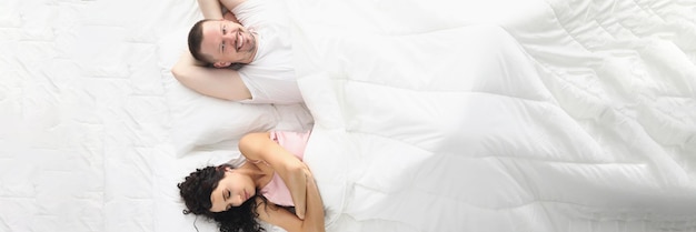 아내와 남편이 행복하게 침대에 누워 흰색 침구