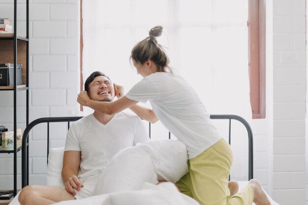 Foto la moglie e il marito giocano a cuscino, litigano e ridono sul letto.