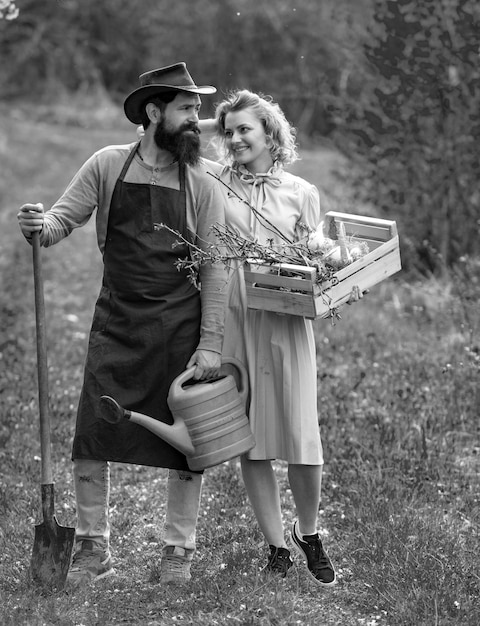 Photo wife and husband spend time in the orchard a pair of farms carries boxes with vegetables and greens