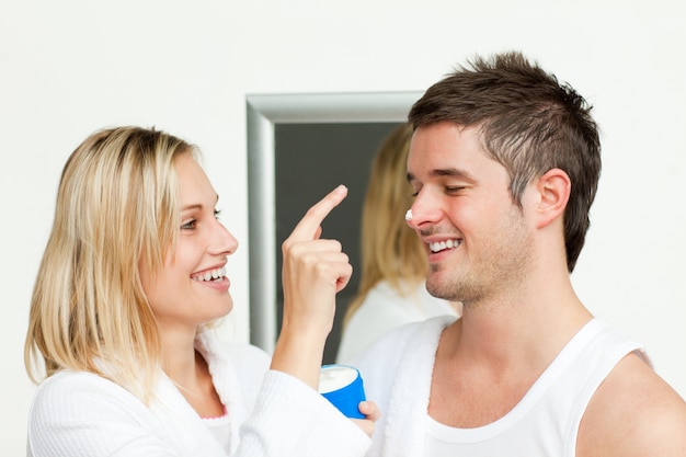 Wife putting cream on his husband's nose