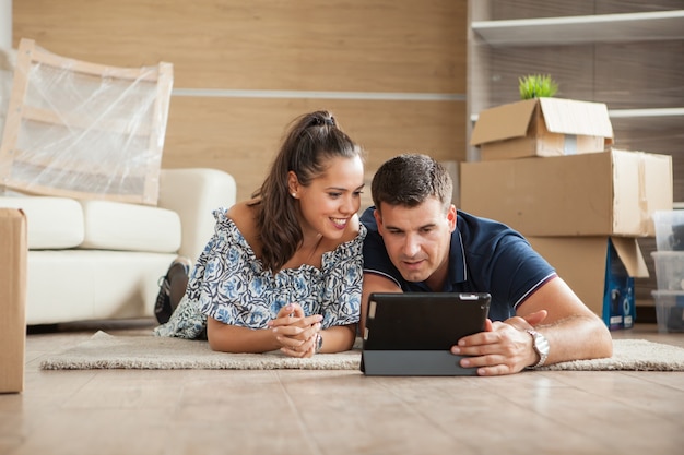 Wife showing to her husband the bed for their new flat on their tablet