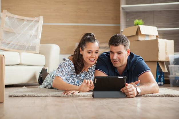 Wife showing to her husband the bed for their new flat on their tablet