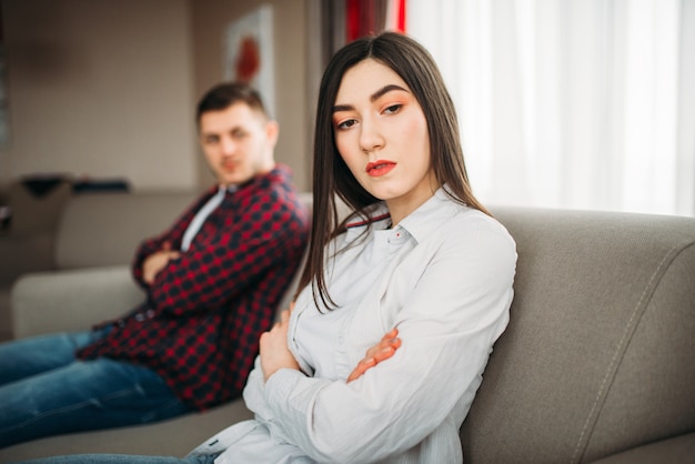 Photo wife sits on couch, angered husband yells on her