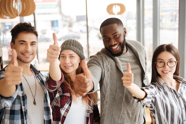 Wij zijn winnaars. De groep jonge gelukkige internationale studenten bevindt zich en beduimelt omhoog.