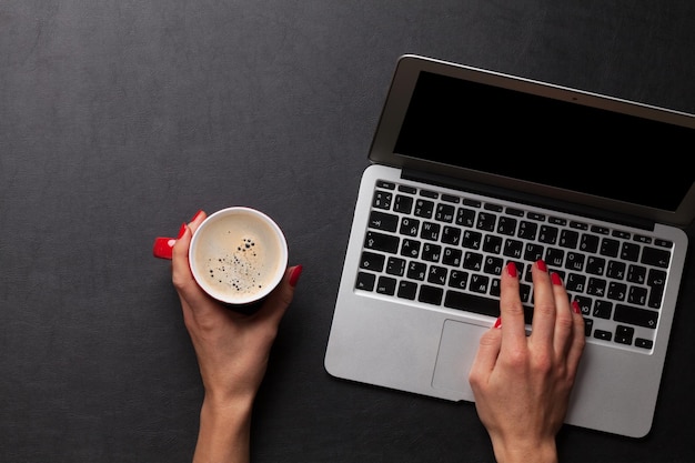 Wijfje dat aan laptop met koffiekopje werkt