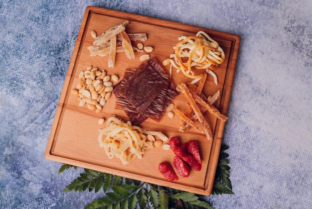 Wijn- en snackset Verscheidenheid aan kaas, olijven, prosciutto, geroosterd stokbrood, plakjes druiven op een houten bord en glazen rode wijn over grijze marmeren achtergrond, selectieve aandacht, vierkant gewas