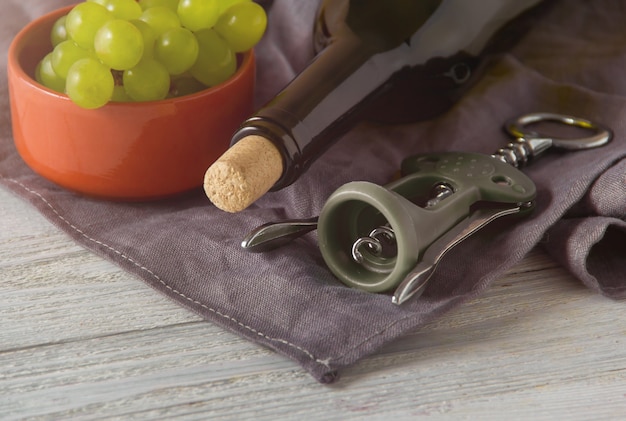 Foto wijnflessen, glas, kurkentrekker, druiven op tafel