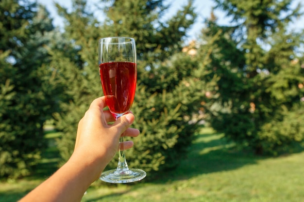 Wijnglas met rode champagnetribune op houten lijst bij groen de zomerpark