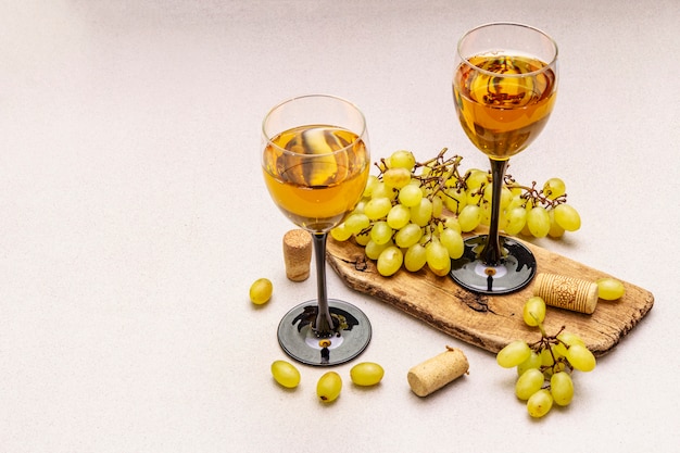 Wijnglazen, verse druiven en kurken op houten snijplank