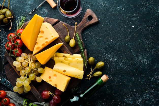 Wijnkaas en snacks op een zwarte stenen achtergrond Geassorteerde kaas Bovenaanzicht Vrije ruimte voor uw tekst