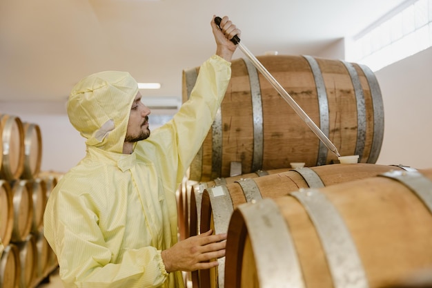 Foto wijnmaker specialist werk in win fabriek test wijn smaak aroma fermentatie in eikenhouten vat tank