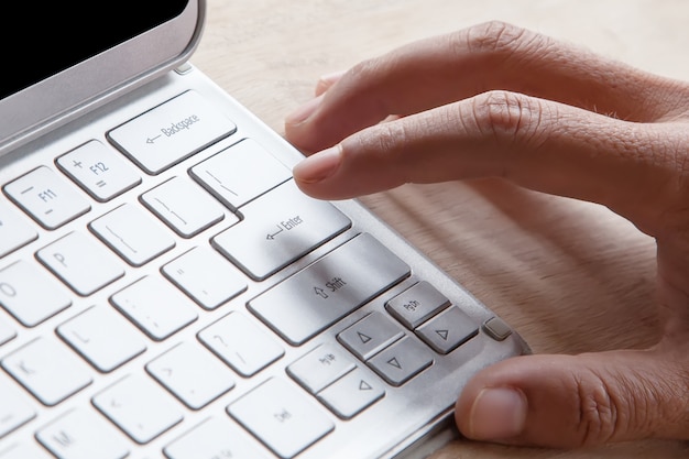 Wijsvinger op knoop van zilveren kleurentoetsenbord op tabletcomputer