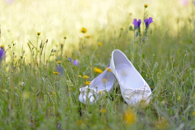 Sfondo selvaggio con fiori pimaveral sfocati e scarpe bianche di una ragazza per la comunione