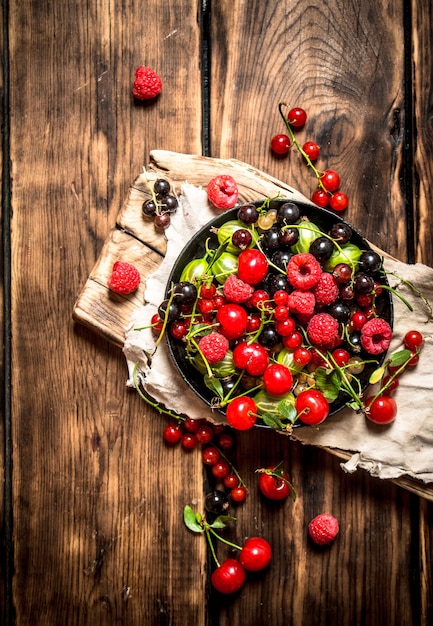 Wild berries in the old plate on wooden table.