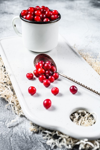 Wild cranberries on a white chopping Board. Gray background. Top view