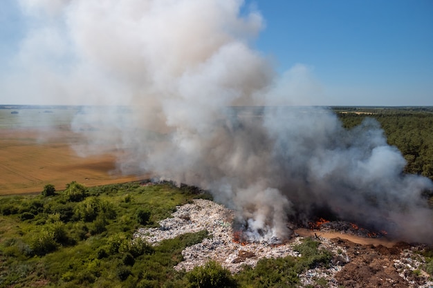 ゴミ捨て場での山火事。町のゴミ捨て場で燃えるゴミからの白と灰色の煙