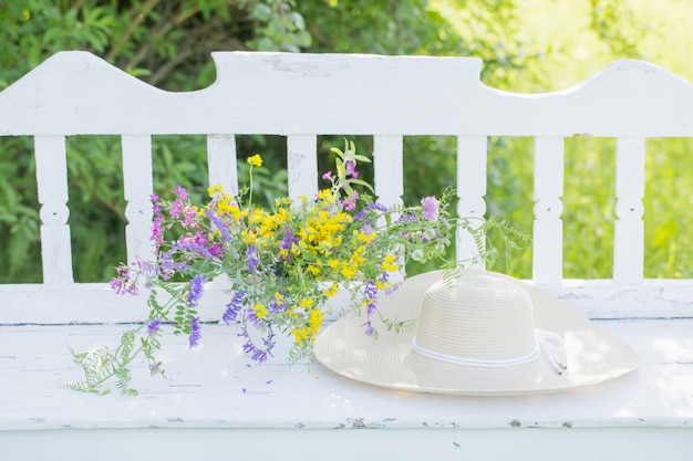 写真 夏の庭の白い木製のベンチの野生の花