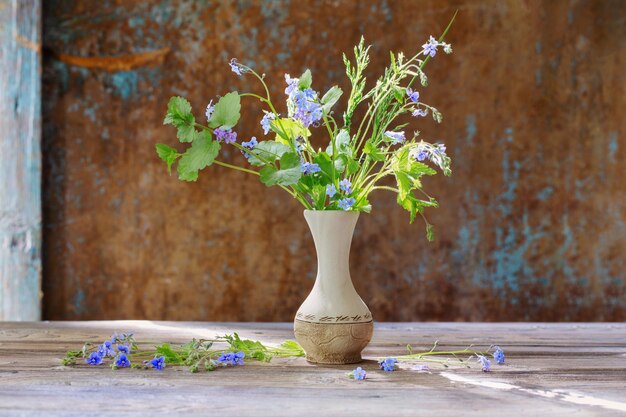 背景の古い壁に花瓶の野生の花