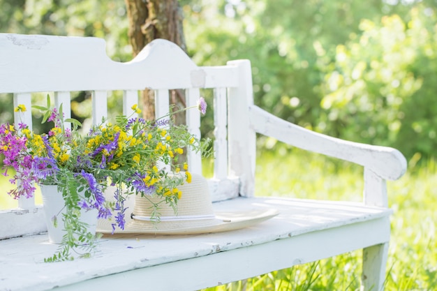 Wild flowers on white wooden bench in summer garden