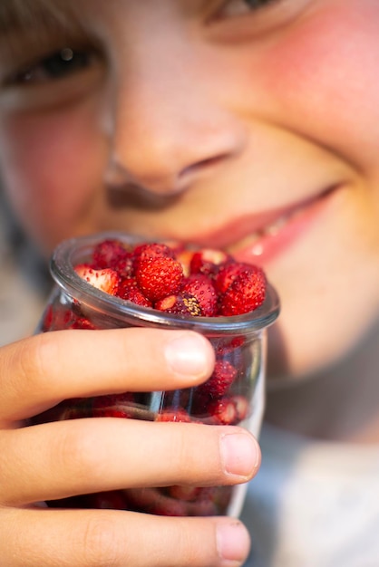 Wild forest strawberries in a jar in the hands of a child