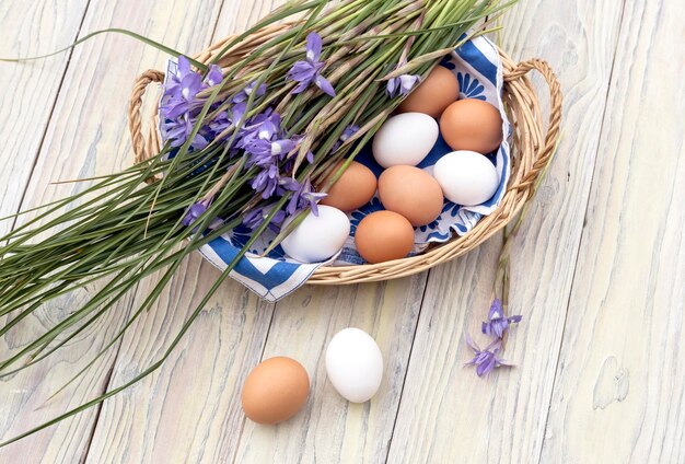 Wild purple irises and a basket with easter eggs on wooden background closeup