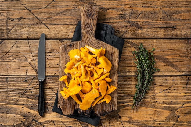 Wild Raw uncooked Chanterelles mushrooms on a cutting board.  Wooden background. Top view.