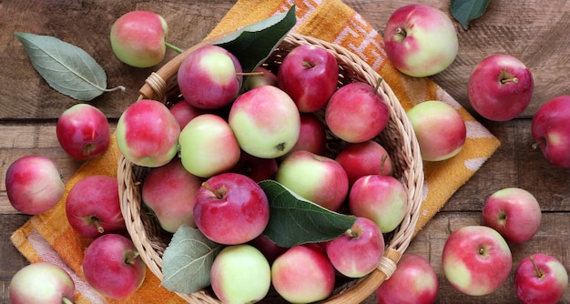 Wild red apples in a basket on a rough table, top view