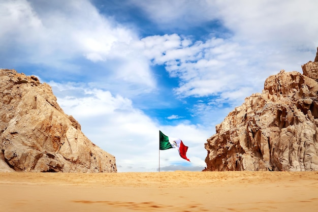 Wild verlaten strand in lager californië van mexico rotsformaties op geel zand tegen een blauwe lucht met witte wolken en mexicaanse vlag