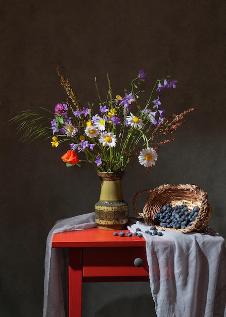 Wild wildflowers in a green vase Basket with blueberries