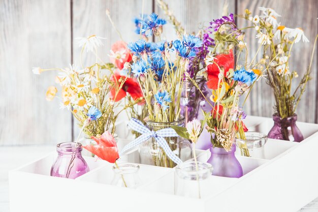 Wilde bloemen in flessen in de doos. Keuken bloemen decor