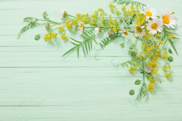 Wilde bloemen op groene houten achtergrond