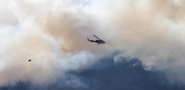 Wildfire Service Helicopter flying over BC Forest Fire and Smoke on the mountain near Hope