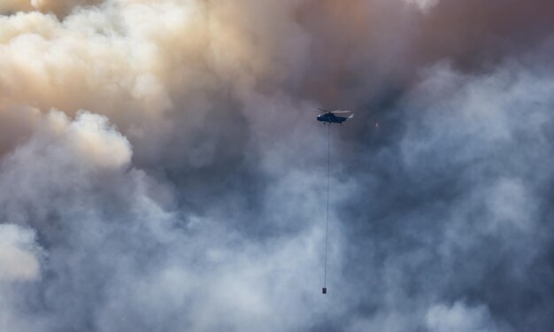 Вертолет службы пожаротушения пролетел над Британской Колумбией. Лесной пожар и дым на горе возле Хоуп