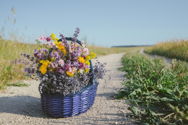 かごの中の野花。フィールドロードのバスケットにさまざまな花の花束。トーン。